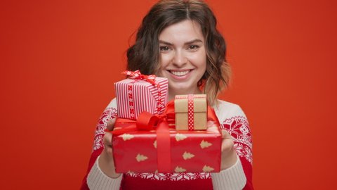 Christmas gifts Portrait Happy young woman face gives Christmas gifts box to family friends stretches out his hands to camera in looking smiling on yellow background. Happy New Year. Noel Festive mood
