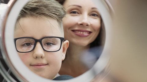 "Boy teenager checks eyesight and puts on glasses
in the optics store of the ophthalmological clinic. The ophthalmologist looks into the roar and smiles"
