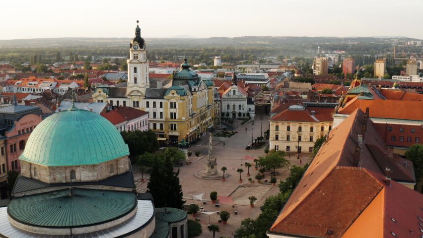 Empty Szechenyi Square In Pecs City, Hungary With The Famous Statue Of Trinity At Sunrise. aerial approach