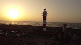 Aerial side view of the Toston lighthouse at sunset, Punta Ballena, near the town of El Cotillo, Fuerteventura island, Canary Islands. Spain, 4k video