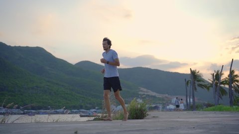 Slow Motion shot of a young man running barefoot. Barefoot running concept