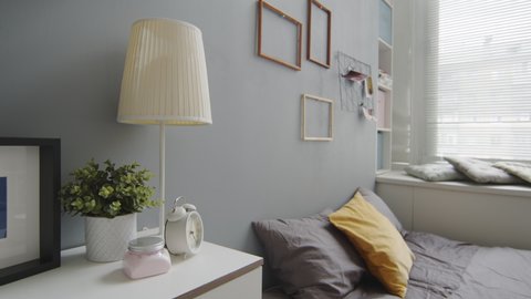 No people slowmo shot of interior design of modern cozy bedroom with grey walls, comfortable bed and photo frames on walls