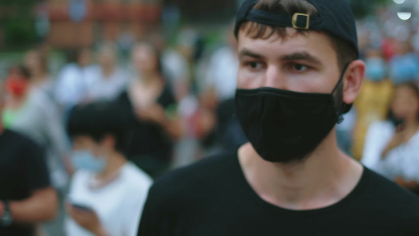 Masked rebel activist man in covid-19 regulations resistance picket crowd on rally revolt. Male protester on political riot demonstration. Opposition guy in restriction coronavirus facemask claps hand Royalty-Free Stock Footage #1080916118