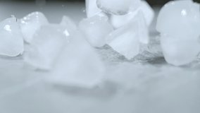 SLOW MOTION, MACRO, DOF: Melting pieces of ice get scattered across the empty dining table. Odd shaped ice cubes fall and bounce around the marble countertop. Ice cubes bouncing around the counter. - Powered by Shutterstock - Get 15% off with code: PIKWIZARD15