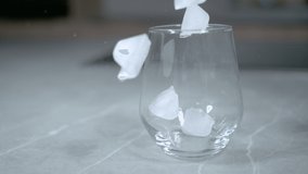 SLOW MOTION, CLOSE UP, DOF: Large cubes of ice fall into the empty vintage glass sitting on the marble kitchen table. Cinematic close up shot of pieces of ice bouncing around an empty soda glass. - Powered by Shutterstock - Get 15% off with code: PIKWIZARD15