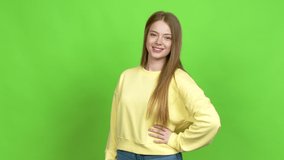 Teenager girl posing with arms at hip and laughing over isolated background. Green screen chroma key