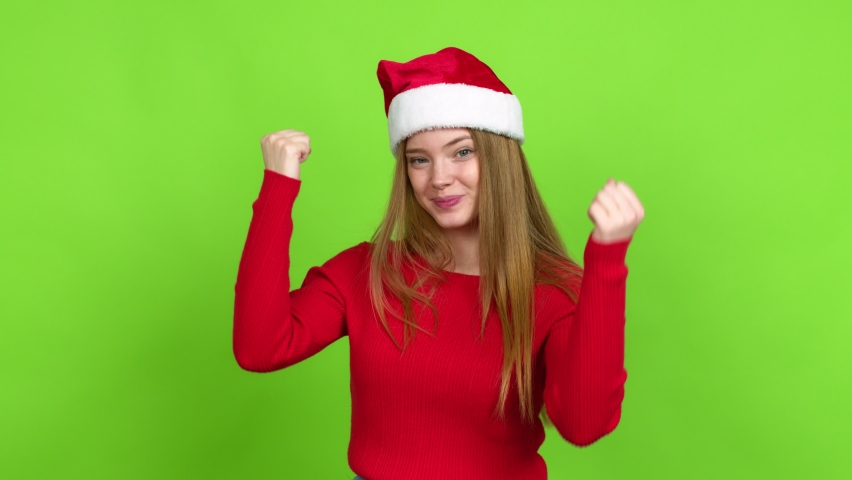 Teenager girl with christmas hat celebrating a victory and surprised to be successful over isolated background. Green screen chroma key