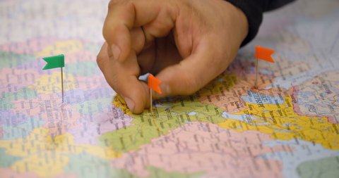 The male hand of an employee sticks flags into the map of Russia, which indicate the key points of transportation of industrial cargo
