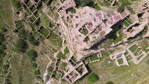 Amazing aerial 4k drone footage - top down flight over the lost ruined ancient city Gamsutl. High Caucasus mountains covered with green forests on the background. Dagestan, Russia.