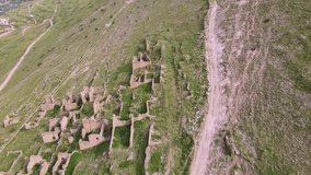 Amazing aerial 4k drone nature footage - flying over old city ruins toward high green rocky mountains of Caucasus. Dagestan, Russia