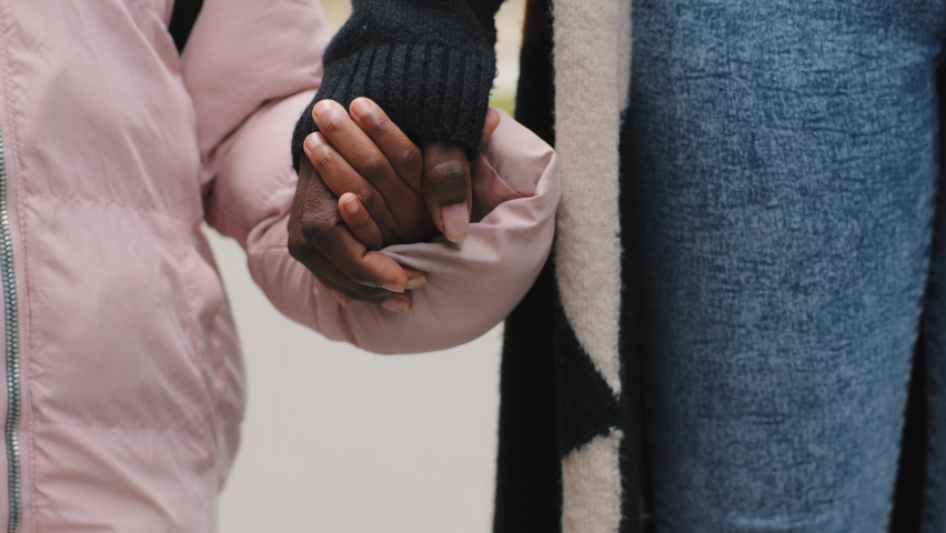 Close up unrecognizable african american black mother woman and daughter child kid son baby walking outside holding hands together at street walk holiday outdoors. Family bonding relationships concept | Shutterstock HD Video #1080931583