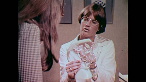 1980s: UNITED STATES: model of cervix and uterus. Lady puts hand inside model. Lady in clinic.