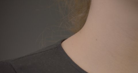 Following a young brunette females neckline from shoulder to ear, close up.