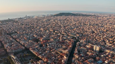Dolly back drone shot over winding streets of north Barcelona Gracia at sunrise
