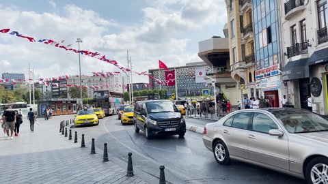 Istanbul, Turkey - August 22, 2021; People walk on the pavement with yellow taxis drive-by