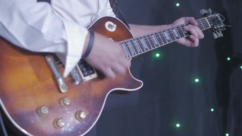 A musician who plays the electric guitar. Close-up of fingers and strings