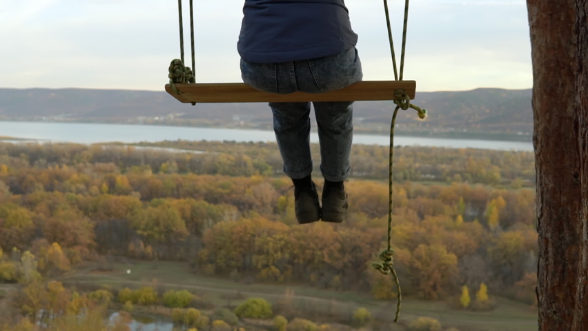 The girl rides on a swing at a high altitude. Swing on the mountain in nature. Spring break on the hill HD