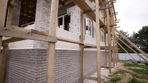 The wall of the house is built of brown and white bricks. Brick wall. The horizontal part of the wall is lined with white and yellow bricks. Brick background. Interior design and concept.