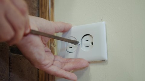 Close up view. Worker electrician repair an electrical outlet in apartment.