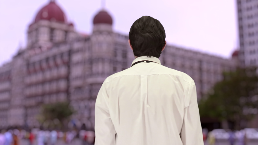 Handsome caucasian Indian boy, with a beautiful dusk background of an ancient architecture building of Bombay. 4K ProRes