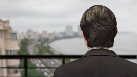 Successful rich millionaire Indian businessman, with defocused background of world famous marine drive queens necklace view from rooftop of luxury penthouse. 4K ProRes 