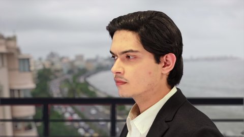 Side profile of Successful rich millionaire Indian businessman, with defocused background of world famous marine drive queens necklace view from rooftop of luxury penthouse. 4K ProRes 