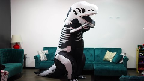 man in skeleton dinosaur halloween costume in the living room of the house
