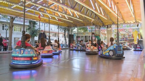 Lugo , Lugo , Spain - 10 15 2021: masked children have fun riding bumper cars at amusement park