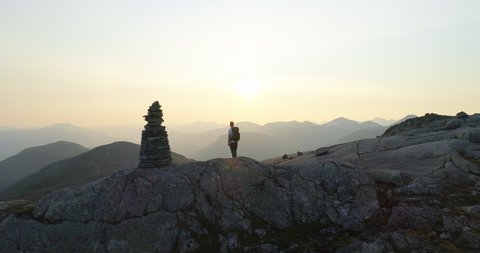 Norwegian hiker alone on mountain overlook fjord view and sunset - aerial orbit