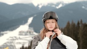 young girl snowboarder is smiling on the top of the mountain