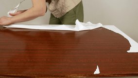 Woman peels adhesive paper off the table.