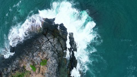 Aerial view Drone camera top down of seashore rocks in a blue ocean Turquoise sea surface Amazing sea waves crashing on rocks seascape Aerial view drone 4k High quality of ocean with stone rock cliff