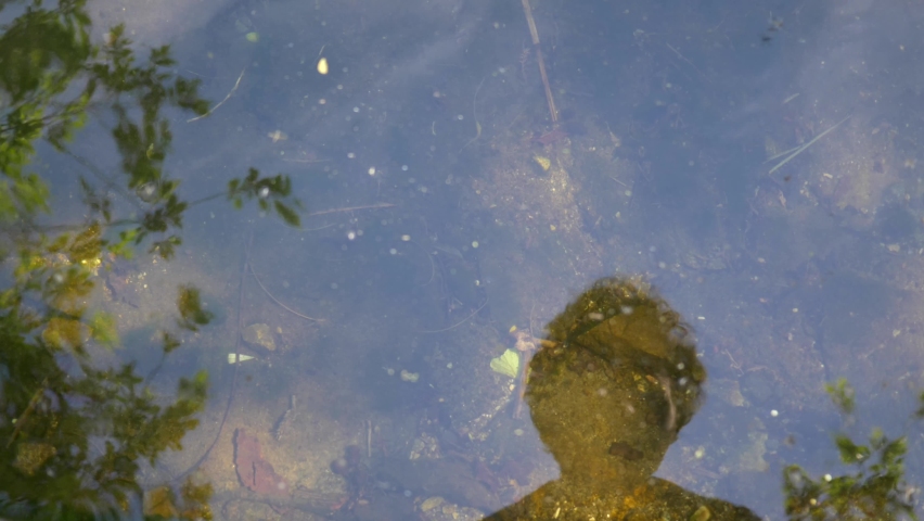 Man's face is reflected in the water of a pond. Slow motion 4K
