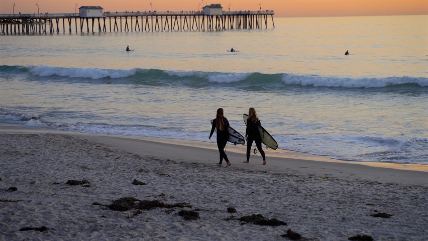 Two surfer girls walking on the beach just after sundown. Slowed to quarter speed Royalty-Free Stock Footage #1080967370