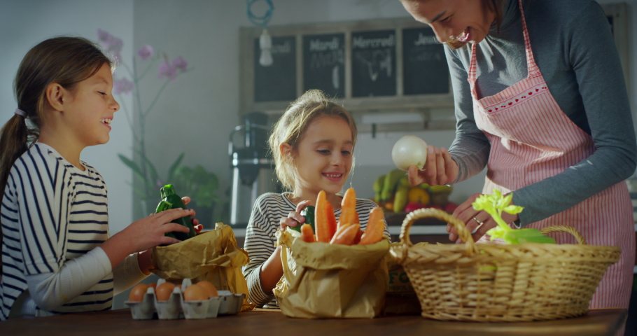 Portrait of a Woman and her Two Daughters Choosing Vegetables for Lunch. Cute Little Girls Helping their Mother in the Kitchen, Preparing to Cook a Delicious Meal Together | Shutterstock HD Video #1080970679