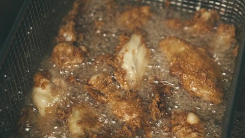 Footage of crispy frying chicken wings, boiling oil
