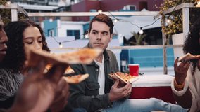 Multi-ethnic female, Caucasian male and diverse group of adult friends eating pizza and socializing on a rooftop at dusk - Powered by Shutterstock - Get 15% off with code: PIKWIZARD15