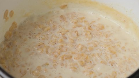 Cooking oatmeal porridge and add butter to the boiling porridge. Close up. Healthy breakfast. 4k video