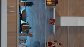Vertical video: Festive woman putting presents on kitchen counter in kitchen designed for christmas eve celebration. Cheerful young person preparing boxes with gifts for friends and family at home