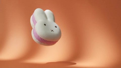Big White and Pink Spongy Rabbit falling down on the orange background. Hare-Shaped squishy Toy Bounces Off Orange Surface in Slow Motion. 500 fps Video stock