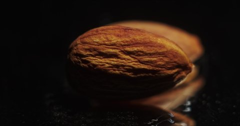 Almonds in a ray of light. Almonds on a black background. The video was filmed in slow motion with a Black Magic  movie camera. 4k