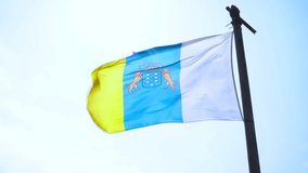 Official Canary Island flag waving in the wind on a sunny and windy day with copy space left.