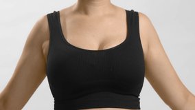 White unrecognizable anonymous lady in black top measures her bust with a tape for bra fitting. Studio still no head shot high quality video on white background.