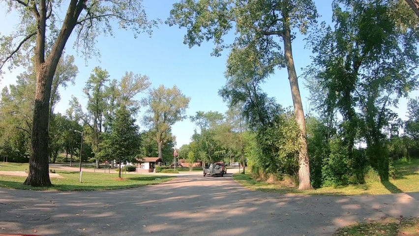 Following a truck that is towing a fishing boat past a part entrance on a sunny summer afternoon along Mississippi River near Hampton Illinois; park is Army Corps of Engineering
