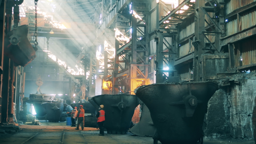 Steel ladle is being relocated by air with plant workers watching it Royalty-Free Stock Footage #1081000853