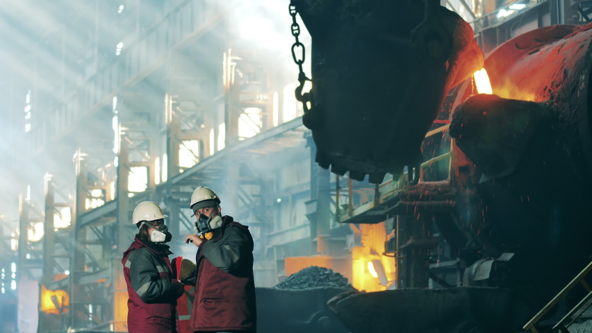 Steelworkers are observing and discussing foundry workshop Royalty-Free Stock Footage #1081000871
