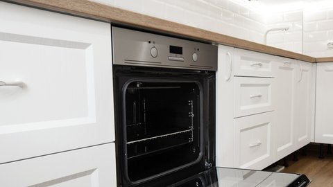 Open oven at white kitchen with wooden countertop and laminate flooring. Nobody