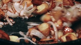 Potatoes with onion are frying in oil.Closeup view.Roasted baby potatoes in iron skillet.Fried crispy potatoes in a pan.The cook is stirring the fried potatoes.Unhealthy and oily food. Fast food. - Powered by Shutterstock - Get 15% off with code: PIKWIZARD15
