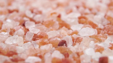 Falling rough crystals of Himalayan salt in slow motion. Macro. Dolly shot.