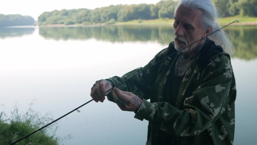 A pensioner collects a fishing rod. Instruction, collection process. Copy space, senior concept. Outdoor, beautiful scenery. threads